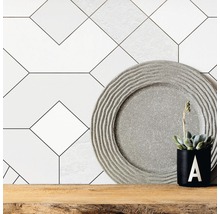Faianță decorativă de perete cu model geometric, farfurie decorativă și plantă în ghiveci pe raft de lemn.