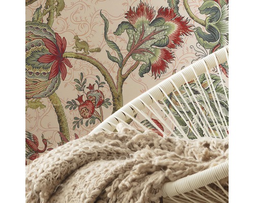 Detaliu al unei camere cu tapet cu model, un fotoliu și o pătură.