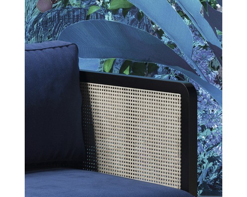 Prim-plan al unui fotoliu albastru cu spătar din ratan în fața unui tapet floral