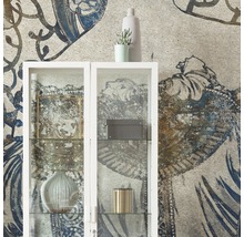 Living decorativ cu un dulap de sticlă alb în fața unui tapet cu model.