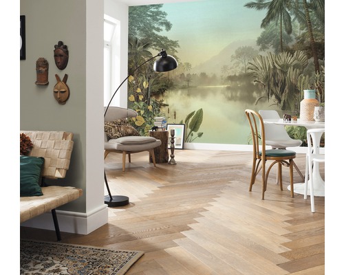 Cameră de zi cu fototapet tropical, podea din lemn cu model herringbone, mobilier de ședere și lampă de podea.