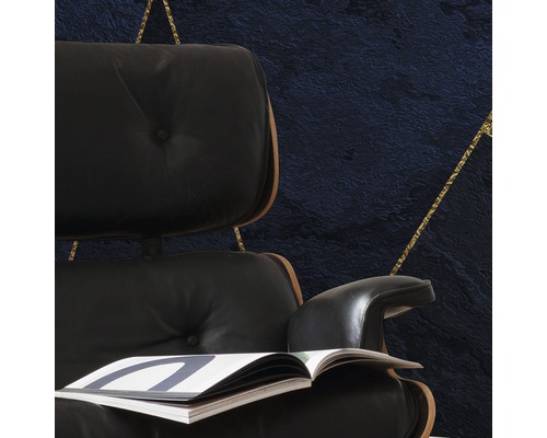 Vizualizare detaliată a unui fotoliu cu revistă în fața unui perete cu model geometric