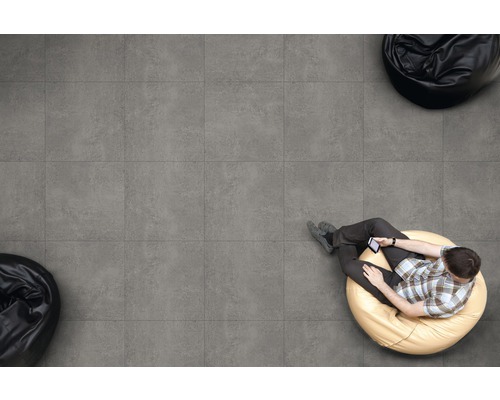 Vedere de sus: persoană așezată pe gresie și folosește telefonul mobil