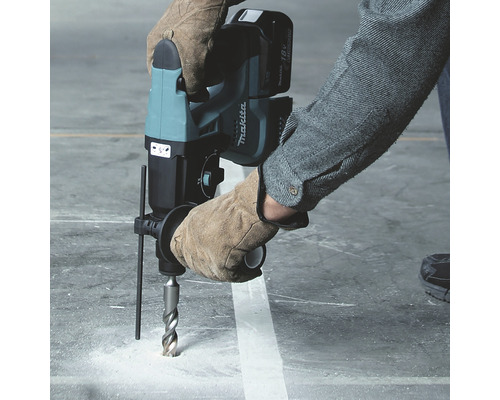 O persoană găurește beton cu un ciocan rotopercutor cu acumulator Makita.