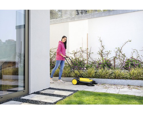 Femeie folosind un aspirator stradal pentru a curăța o terasă