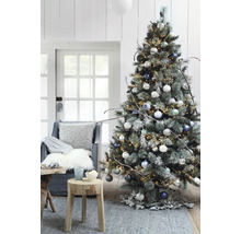 Brad decorat cu luminițe, globuri și decorațiuni rustice într-un living.