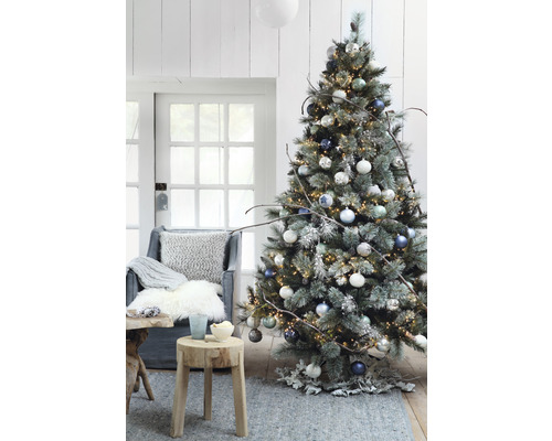 Brad decorat cu luminițe, globuri și decorațiuni rustice într-un living.