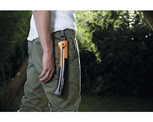 Bărbat cu ferăstrău de mână Fiskars în fixarea pantalonilor în grădină