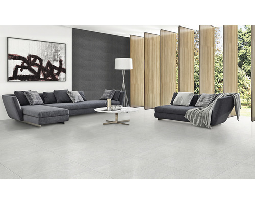 Cameră de zi luminoasă cu gresie, canapea, măsuță de cafea și operă de artă pe perete.