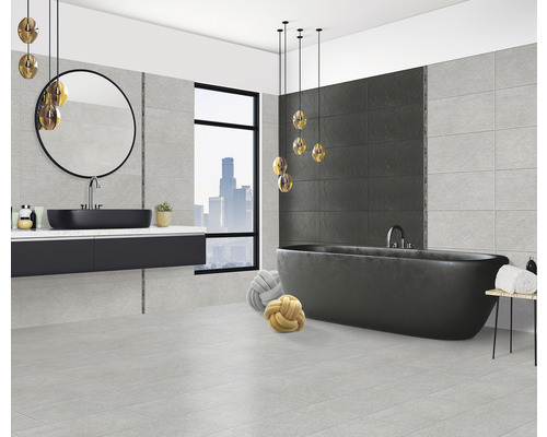 Baie modernă cu cadă, lavoar, oglindă și gresie gri.