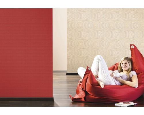 Femeie relaxându-se pe un sac de fasole în fața tapetelor cu model roșu și bej