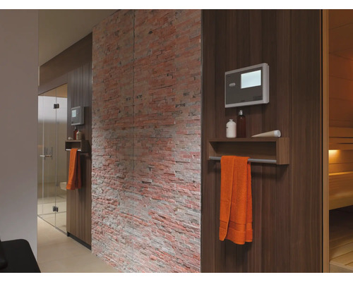 Interiorul unei saune cu lambriuri din lemn, prosop, control și perete decorativ din cărămidă