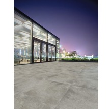 Pavarea cu gresie de exterior în fața unei clădiri moderne, pe timp de noapte.