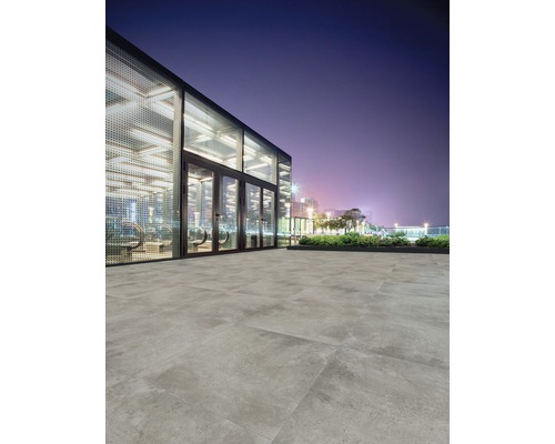 Pavarea cu gresie de exterior în fața unei clădiri moderne, pe timp de noapte.