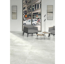 Cameră luminoasă cu gresie, fotoliu și vedere la o stradă aglomerată din oraș.