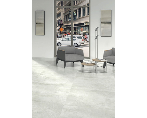 Cameră luminoasă cu gresie, fotoliu și vedere la o stradă aglomerată din oraș.