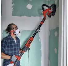 Un bărbat șlefuiește un perete cu o mașină de șlefuit gips-carton Einhell