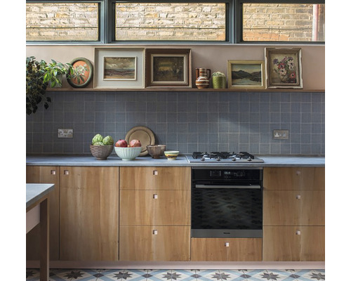 Scenă de bucătărie cu cuptor încorporabil, chiuvetă, dulapuri din lemn, faianță gri și decorațiuni