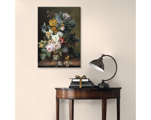 Tablou cu natură statică florală deasupra cărților și o lampă pe o masă