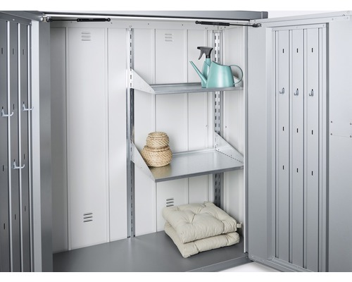 Interiorul unei magazii metalice cu rafturi, perne și o stropitoare