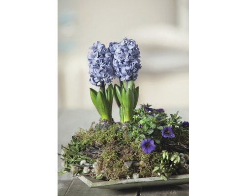 Aranjament cu zambile și alte flori de primăvară într-un vas.