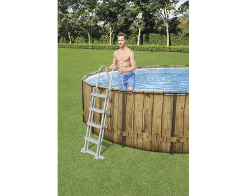 Piscină ovală cu placare din lemn și scară în grădină.