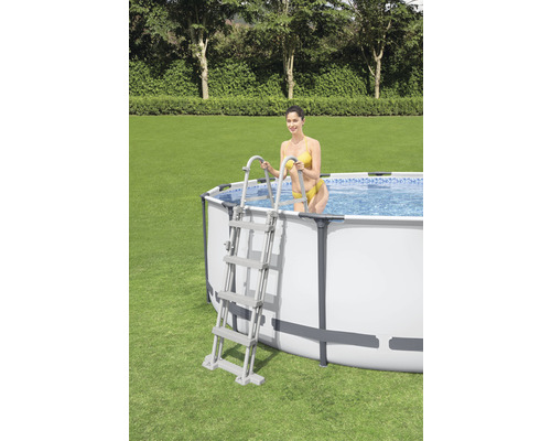 Piscină supraterană cu scară și femeie în grădină.
