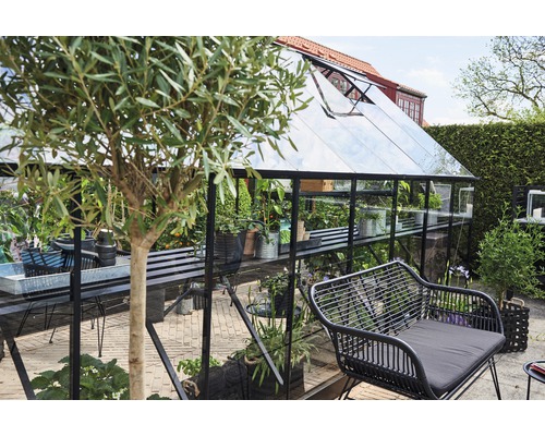 Seră cu plante și zonă de relaxare în grădină.