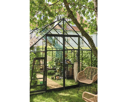 Seră cu plante și unelte de grădinărit într-o grădină