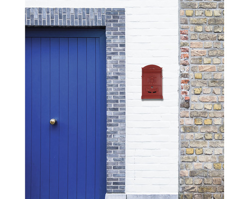 Cutie poștală roșie pe un perete lângă o ușă albastră.