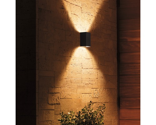 Lumină de perete exterioară pătrată din metal cu efecte de lumină pe un perete de piatră