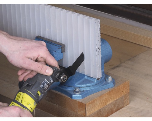 O placă celulară transparentă este prinsă într-o menghină și este tăiată cu un instrument multifuncțional.