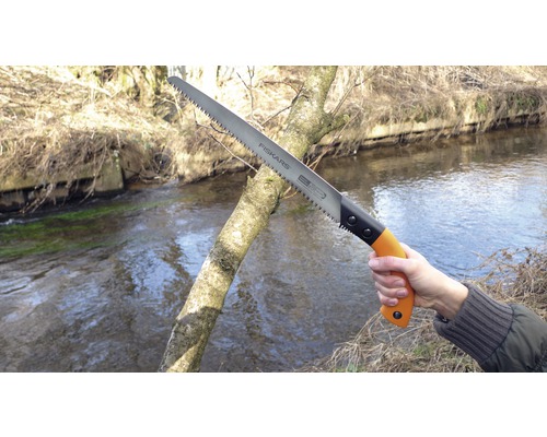 Fierăstrău manual Fiskars care taie o ramură afară