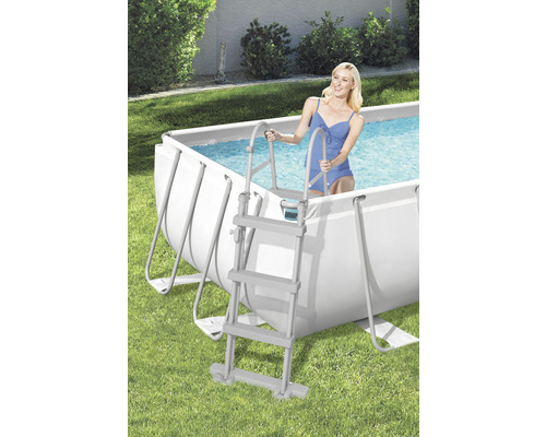 Scenă cu piscină cu cadru din oțel și o femeie care intră în apă pe o scară de piscină