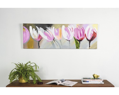 Tablou cu lalele pictat pe perete deasupra unei mese din lemn cu reviste și o plantă la ghiveci.