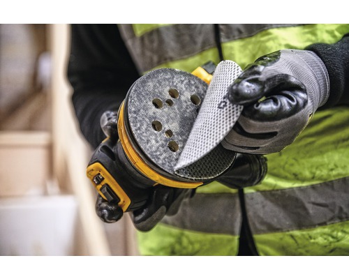 Un bărbat schimbă șmirghel pe o mașină de șlefuit excentrică.