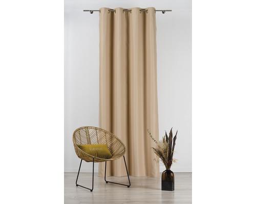 Perdea bej cu ochiuri pe o bară de perdea, lângă un scaun de ratan și o vază cu flori uscate