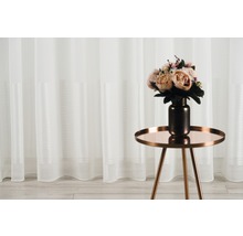 Șaluri decorative cu flori pe o măsuță laterală în fața unei ferestre
