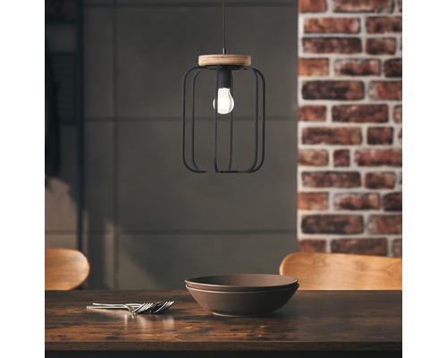 Lampa suspendată cu cușcă metalică și element din lemn deasupra unei mese de sufragerie