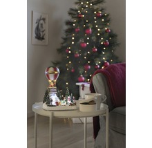 Peisaj decorativ de Crăciun cu balon cu aer cald pe o masă lângă un brad de Crăciun.