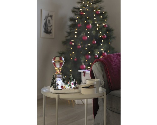 Peisaj decorativ de Crăciun cu balon cu aer cald pe o masă lângă un brad de Crăciun.