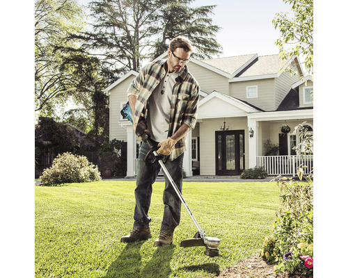 Un bărbat folosește o mașină de tuns iarba în grădină.