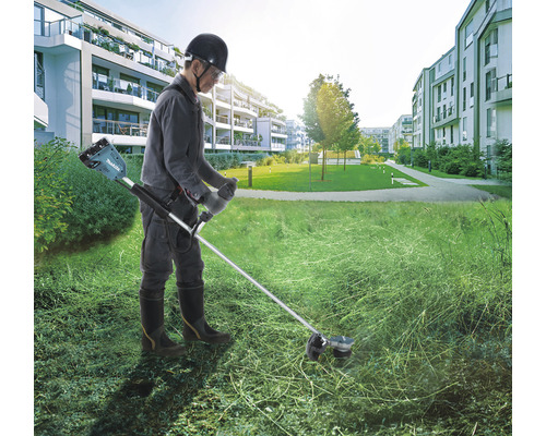 O persoană folosește o mașină de tuns iarba cu acumulator Makita în aer liber.