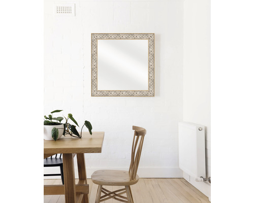 Oglindă decorativă cu ramă din lemn deasupra unei mese de sufragerie pe un perete.