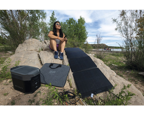 Femeie stând afară lângă un generator solar și un panou solar