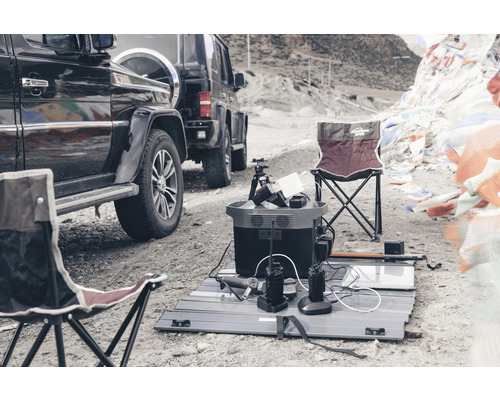 Scenă în aer liber cu centrală electrică portabilă, panou solar, radiouri și scaune de camping