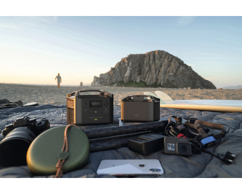 Scenă de plajă cu centrale electrice portabile EcoFlow și dispozitive electronice pe o pătură