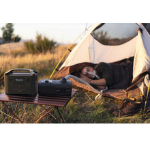 Scenă de camping cu centrală electrică portabilă, aparat CPAP și persoană care doarme
