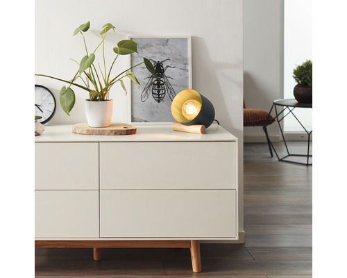 Lampă de masă decorativă pe un bufet într-o cameră luminoasă.