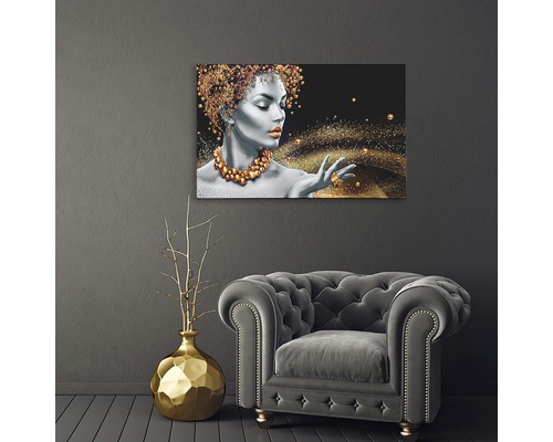 Imagine decorativă de perete cu femeie și accente aurii deasupra fotoliului și vazei aurii
